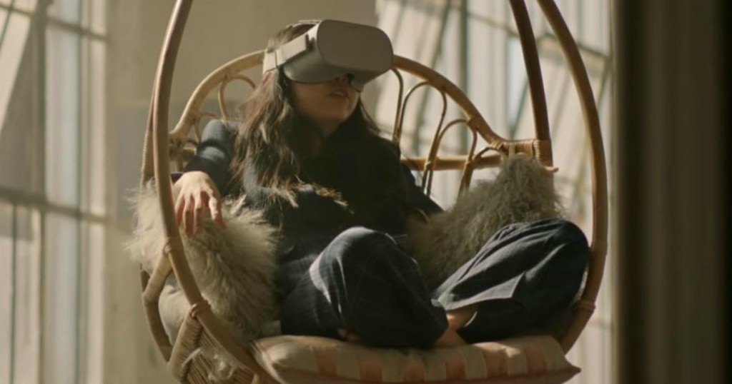 woman in egg chair wearing VR headset by windows