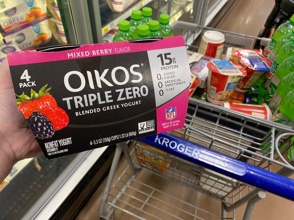 hand holding Oikos Triple Zero in front of Kroger cart