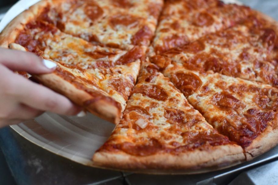 hand grabbing a slice of pizza