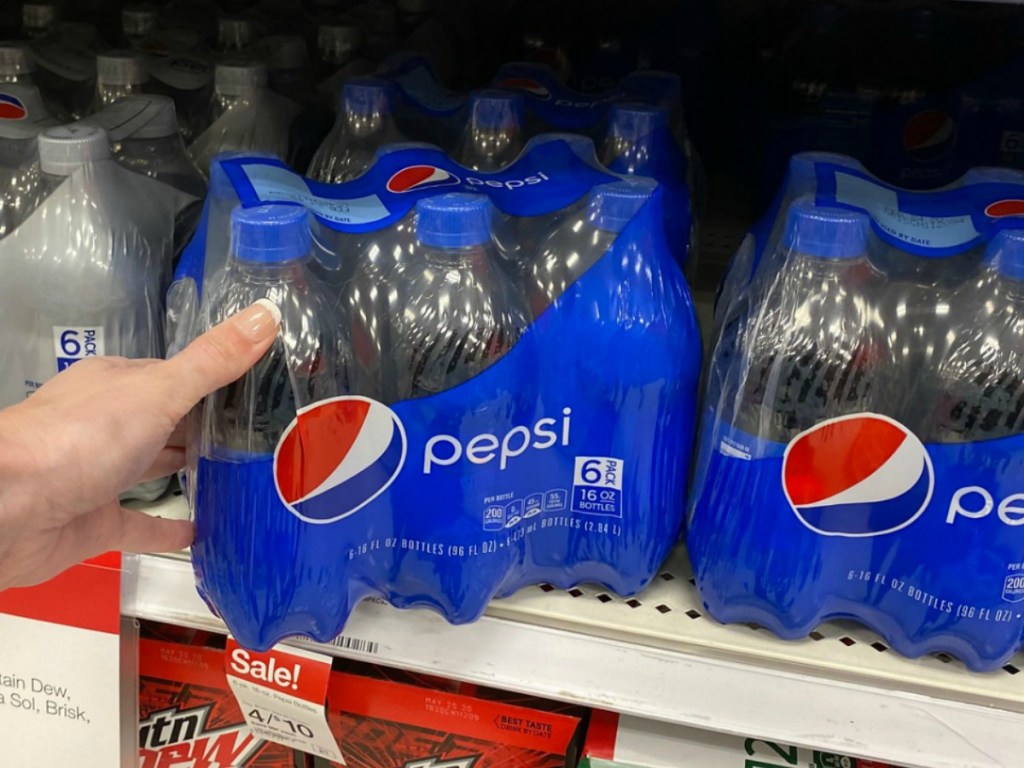 Hand grabbing 6-pack of Pepsi soda bottles from store shelf