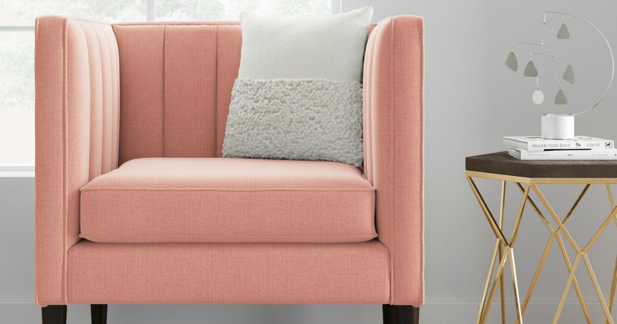 pink chair with pillow on it next to stand