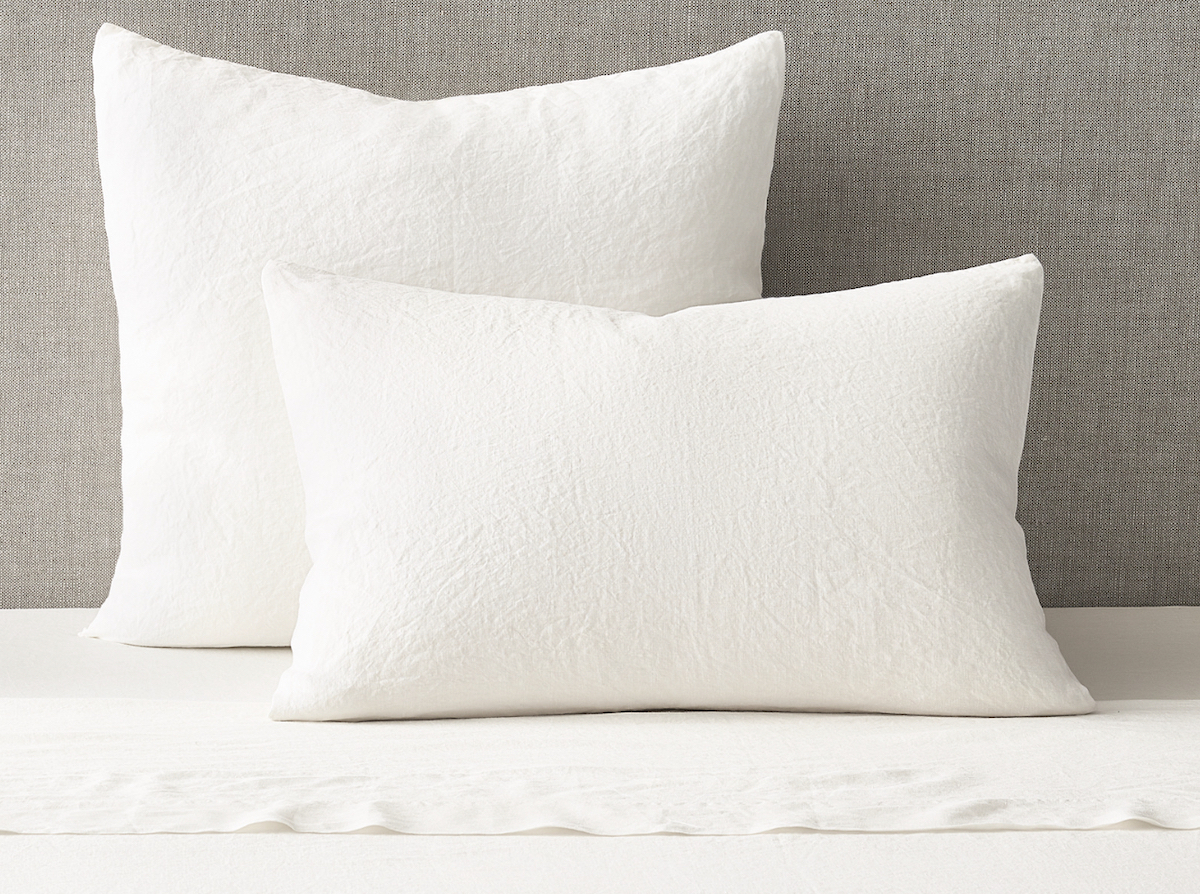 white linen pillows on gray background sitting on white sheet
