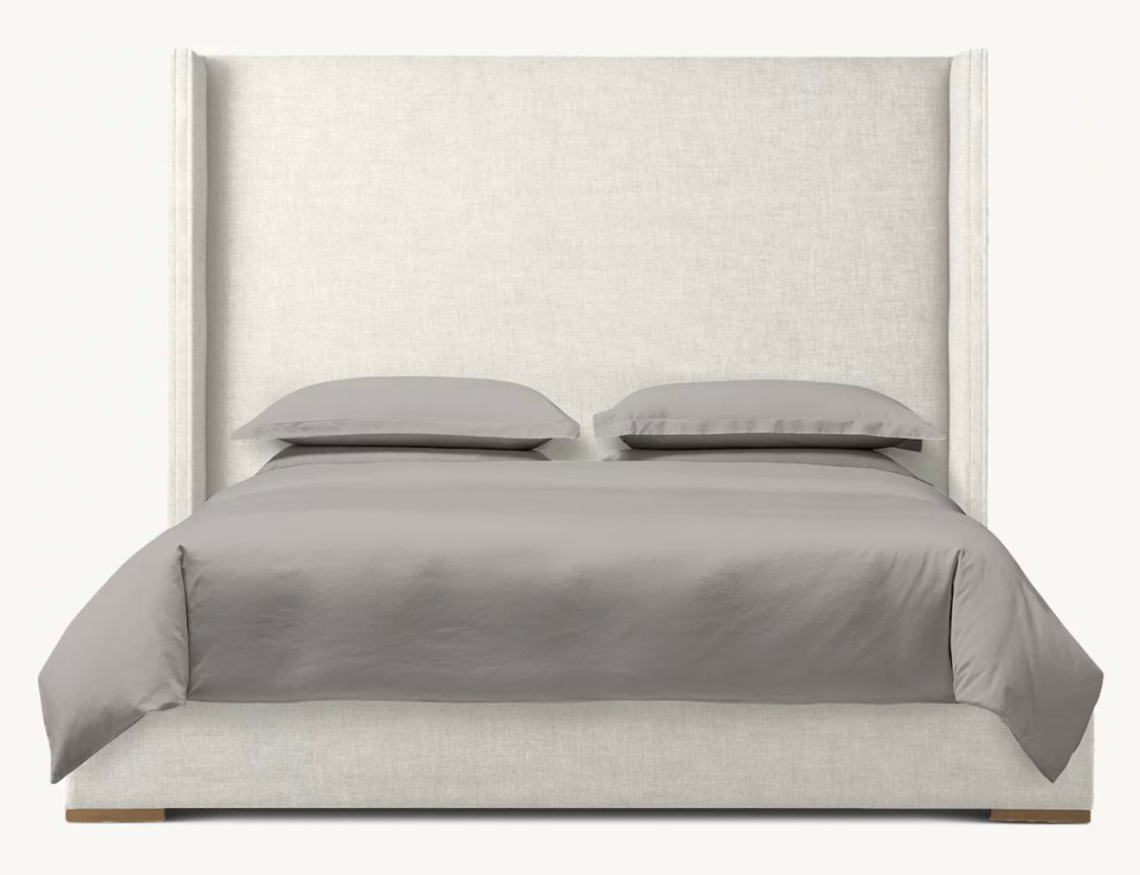 stock photo of beige upholstered bed with gray bedding
