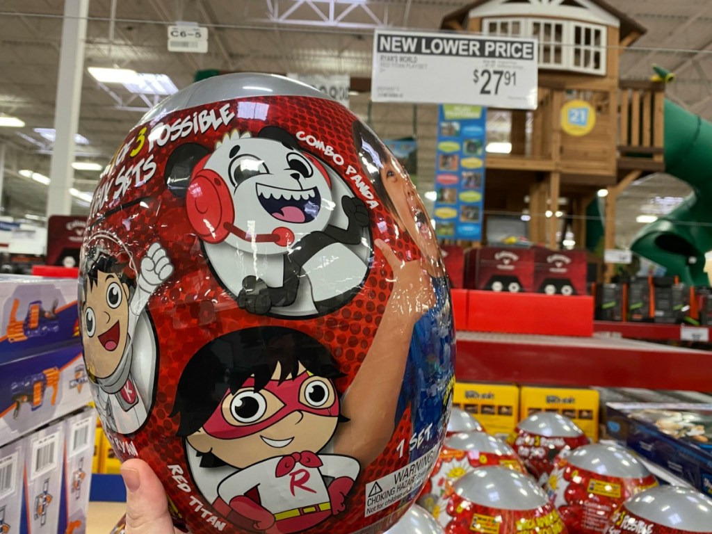 Hand holding a Ryan's world surprise egg near in-store display