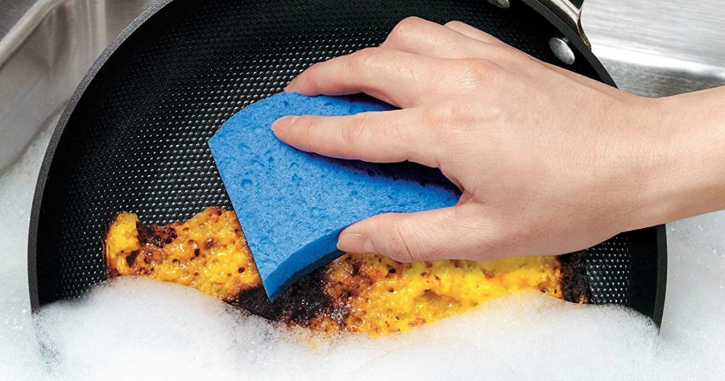 hand cleaning a pan with a sponge