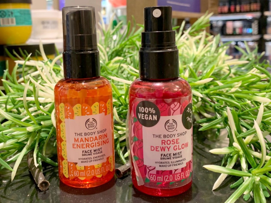 Two spray bottles of face mist on display near in-store decor