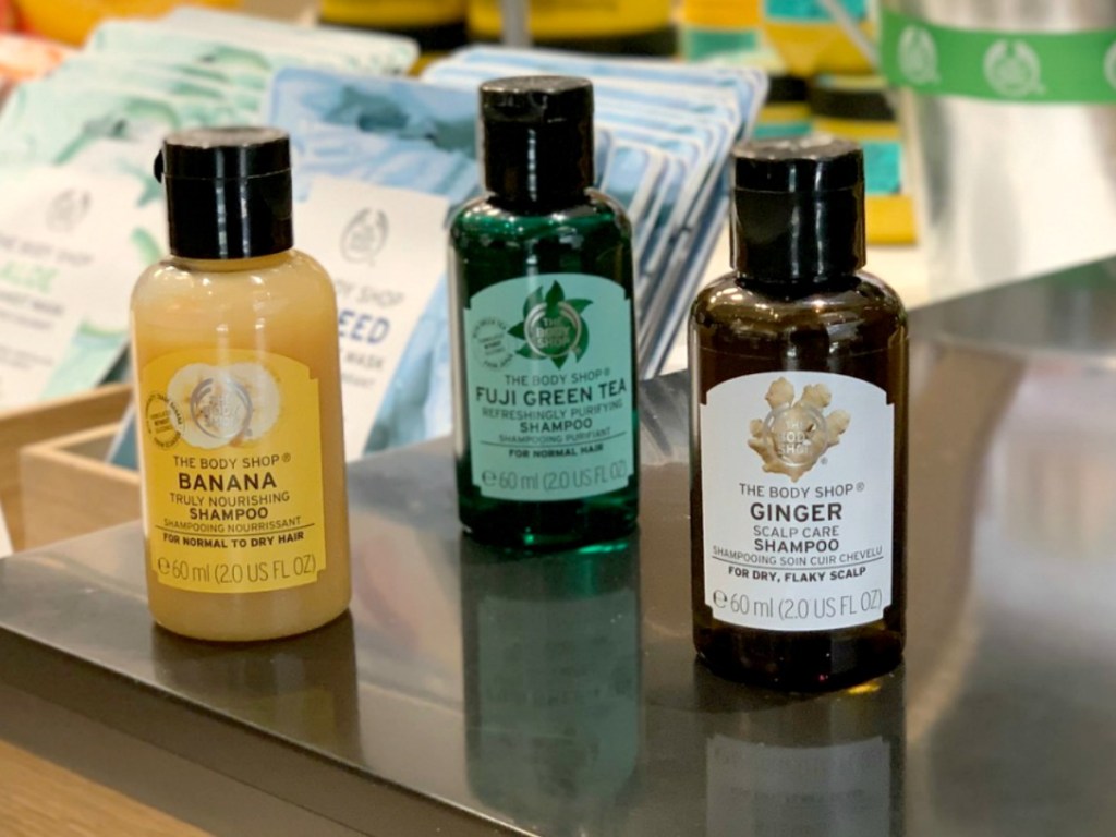 Three small bottles of shampoo on table top in-store in three scents