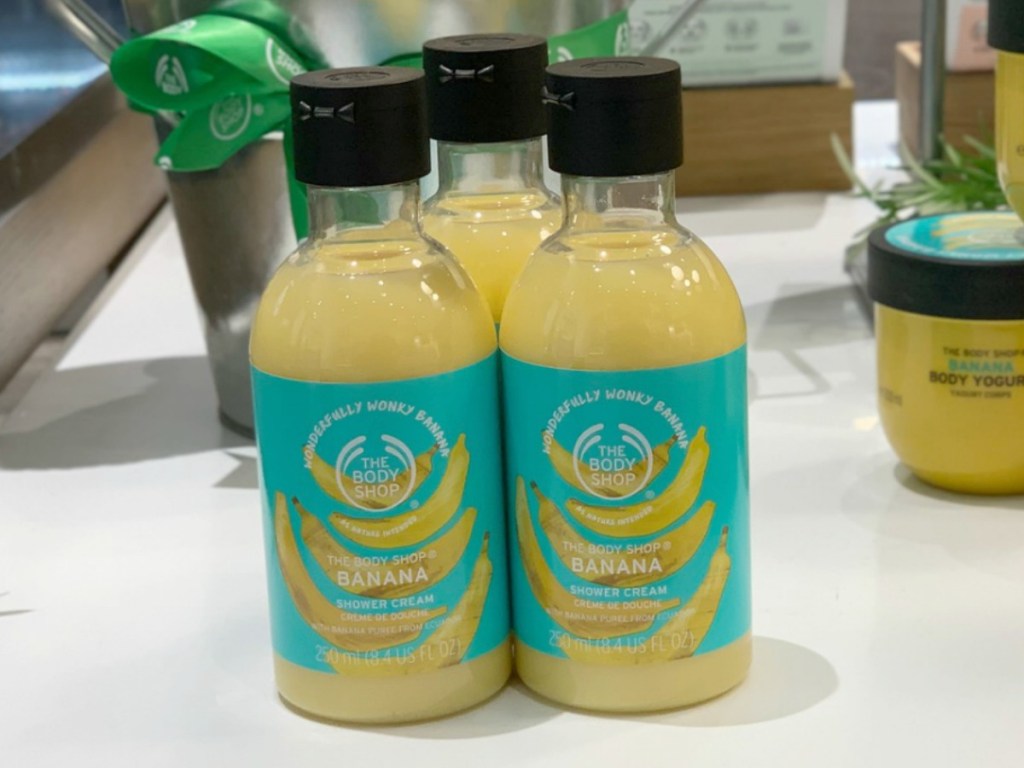 Three bottles of banana scented shower cream in-store on display near other banana scented products