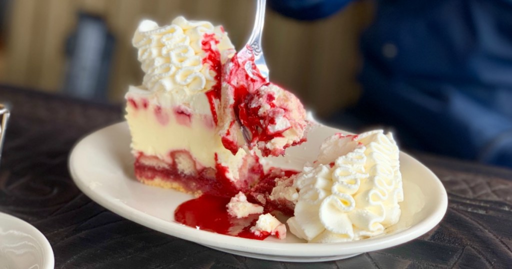 Fork digging into a slice of raspberry cheesecake