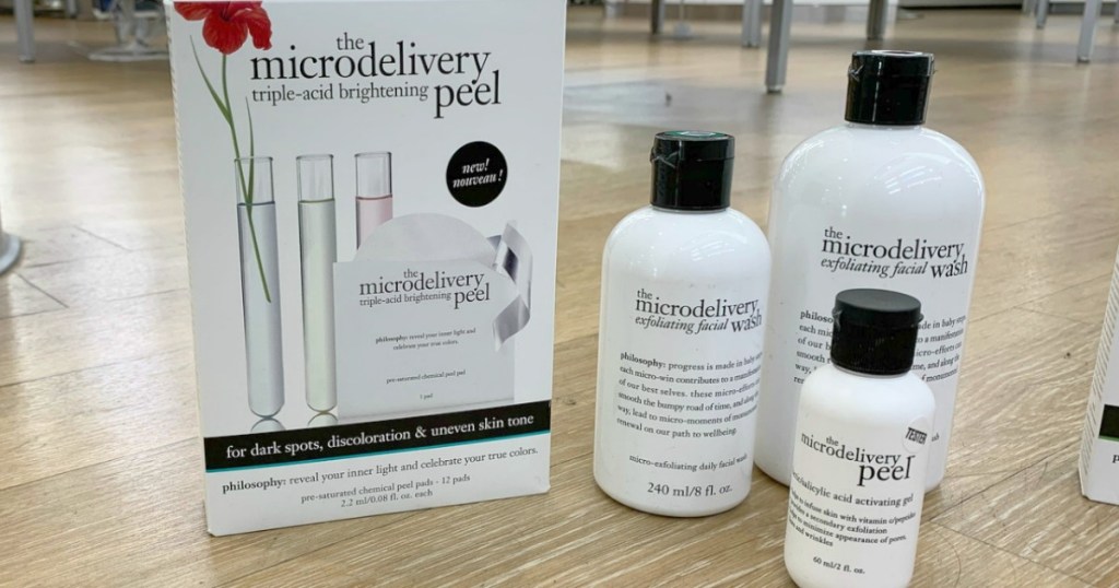 A package of skincare products with bottles of the products on a hardwood floor