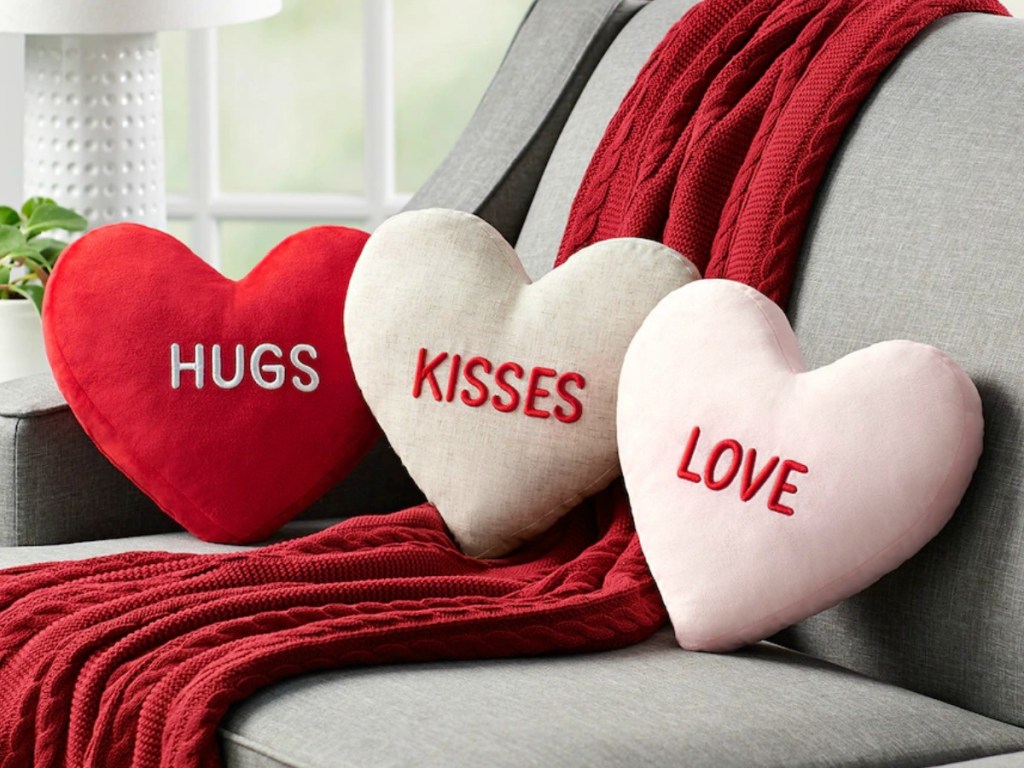 Three heart-shaped throw pillows on sofa with matching red throw blanket