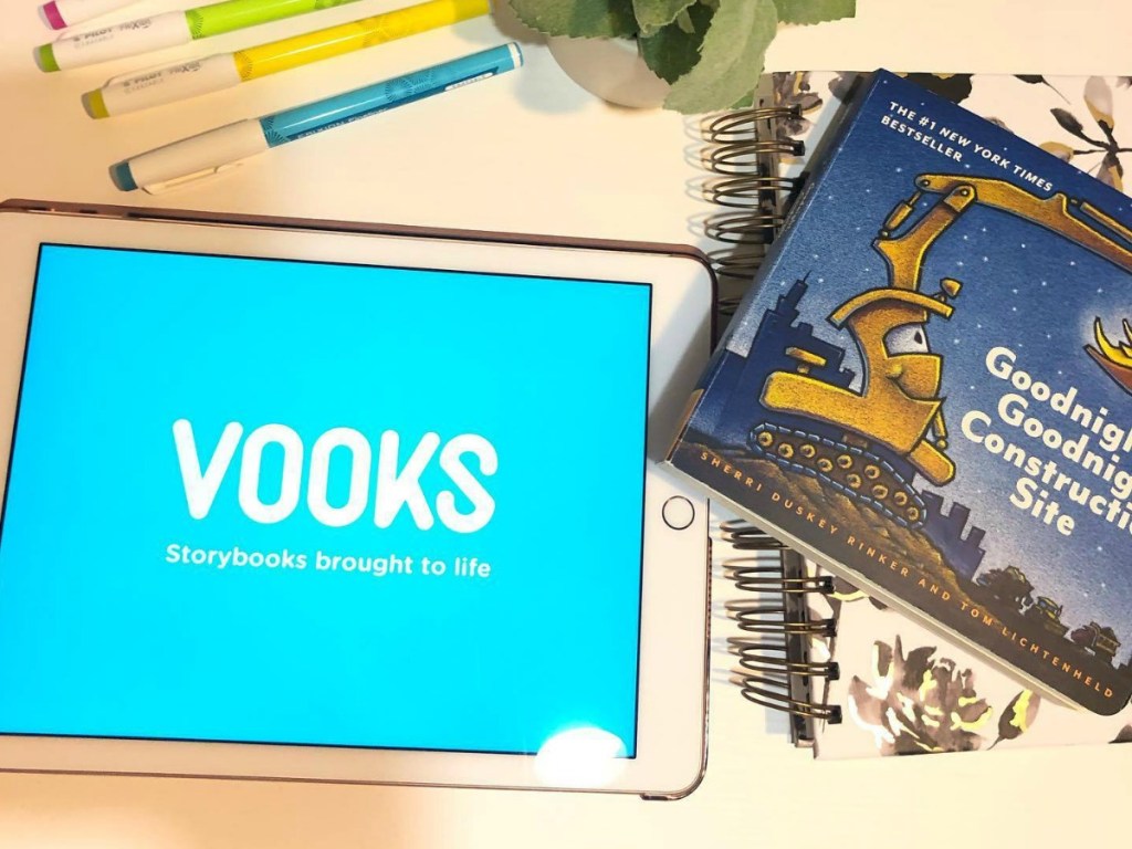 Vooks app open on a tablet near a story book and writing utensils on table top