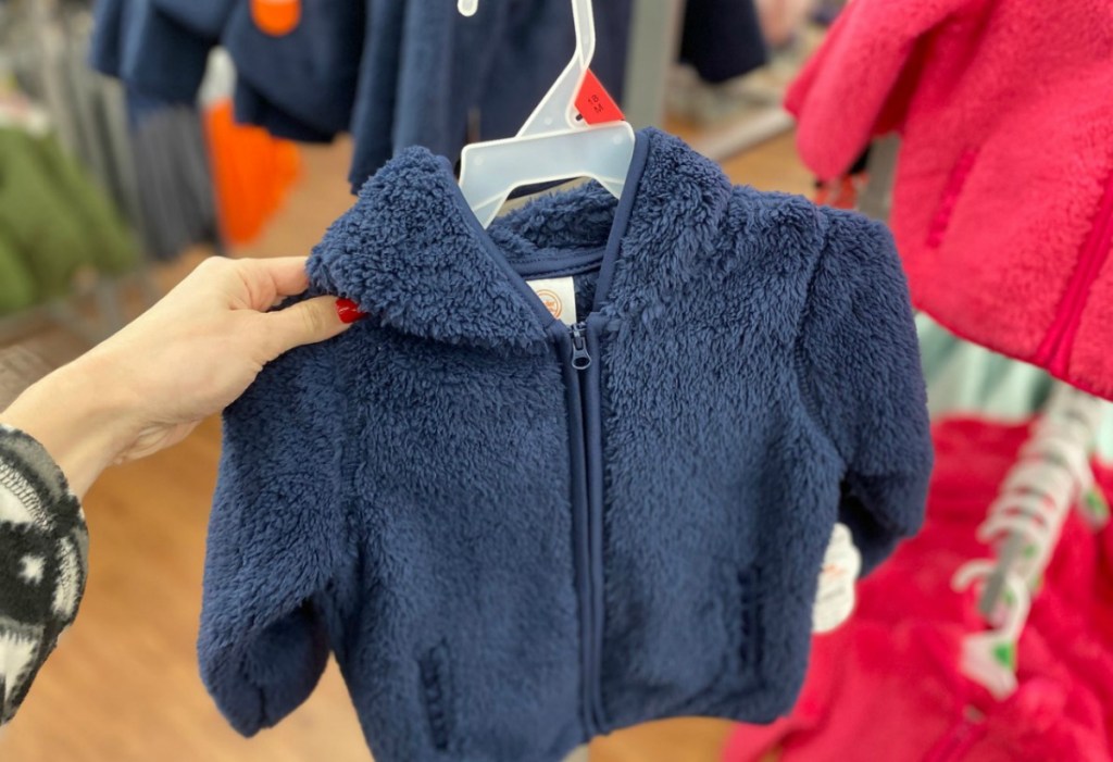 woman holding a navy blue sherpa jacket for a baby girls 