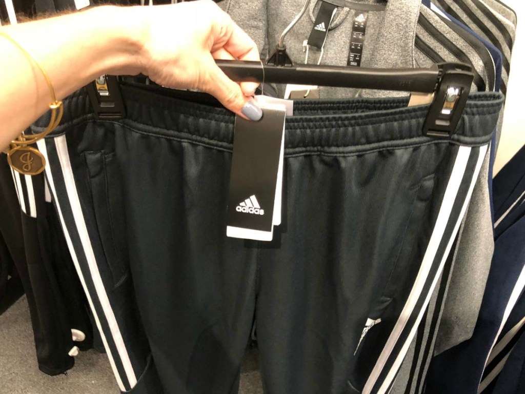 pair of men's athletic pants on hanger in hand near in-store display