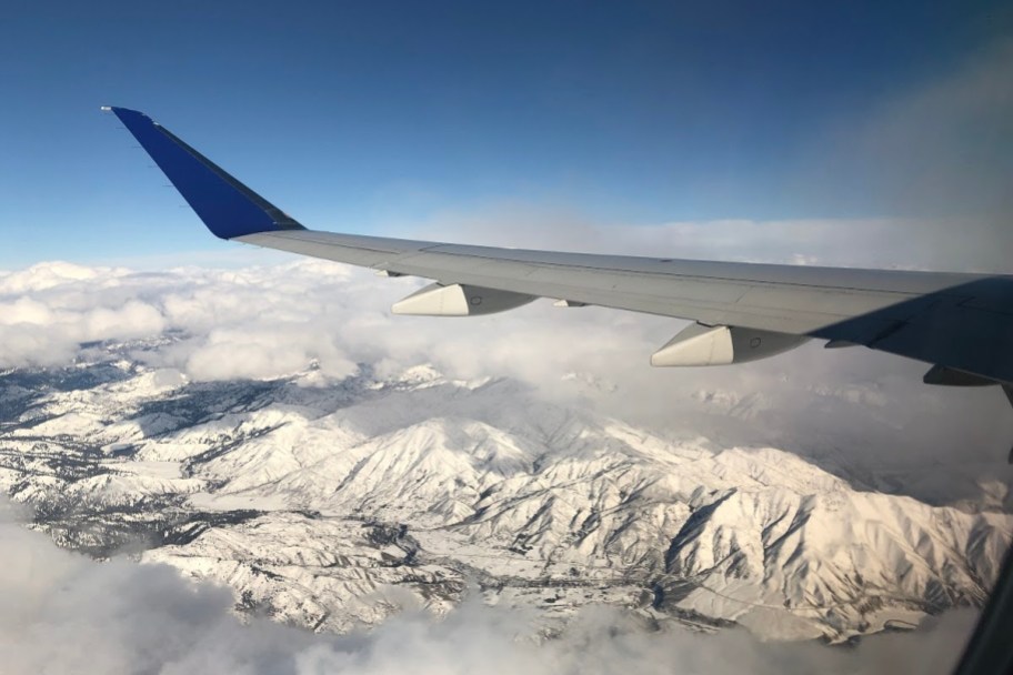 airplane wing over snowy mountains