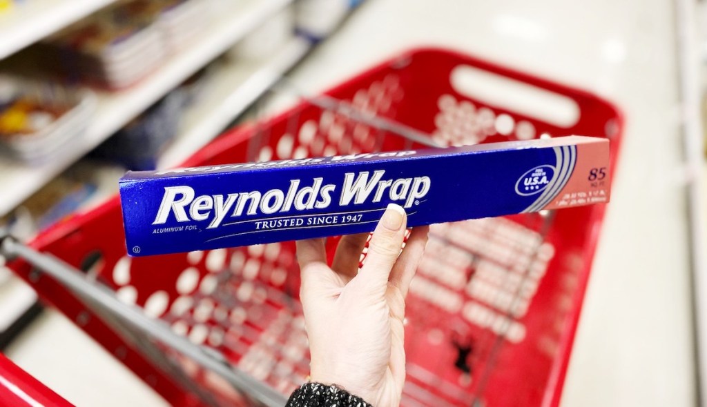hand holding reynolds wrap aluminum foil with target cart in the background