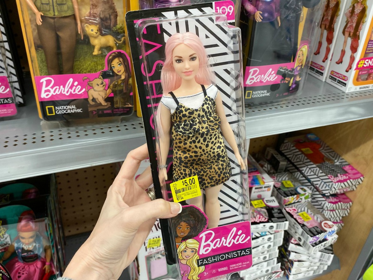 hand holding package with Barbie in it by store display