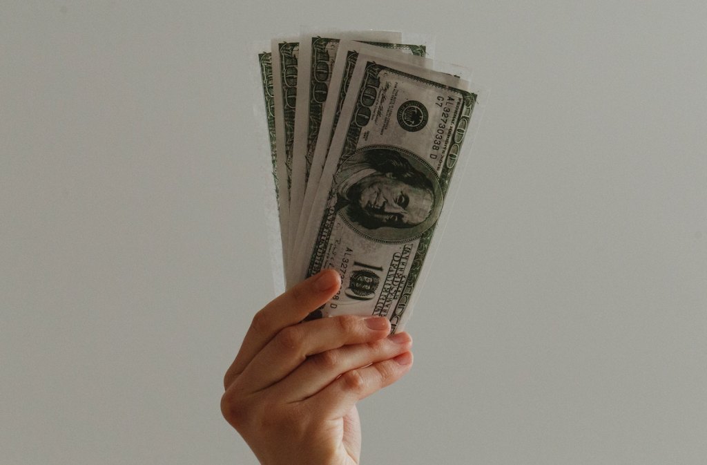 hand holding 100 dollar bills in air
