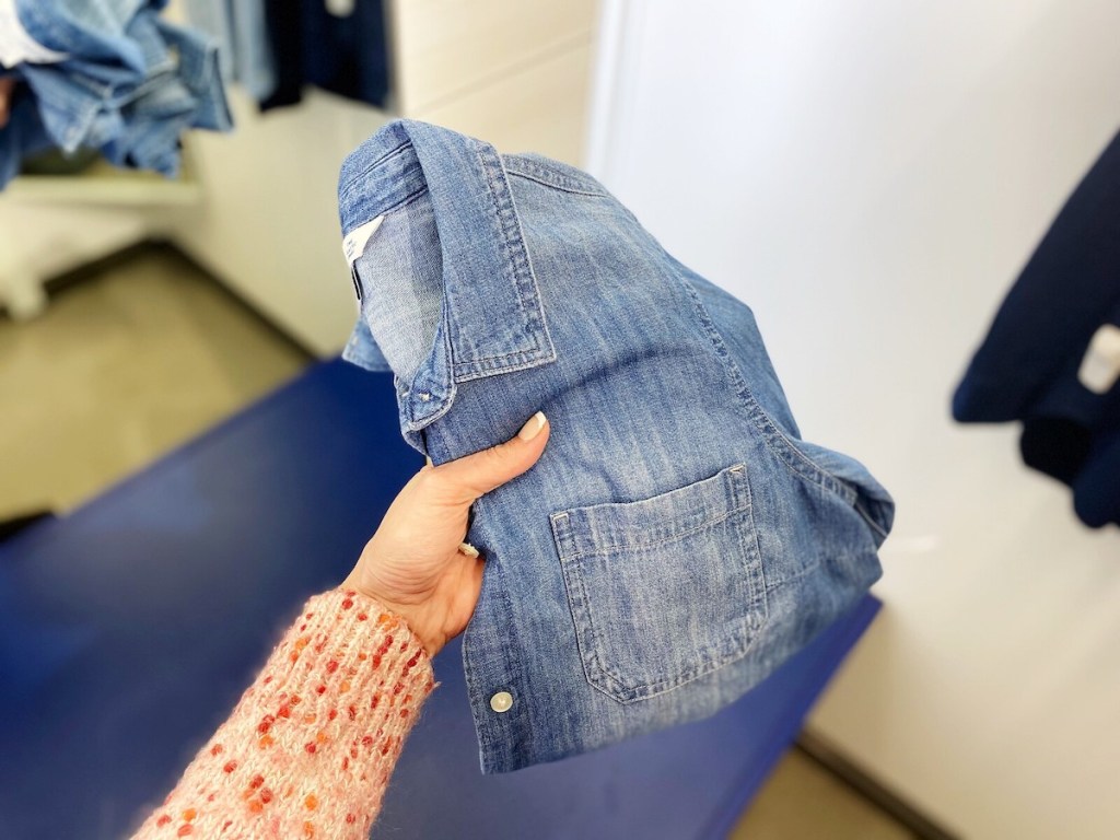 hand holding chambray shirt in dressing room
