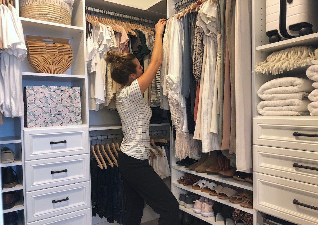 woman standing in walk-in closet with clothes and organized shoes