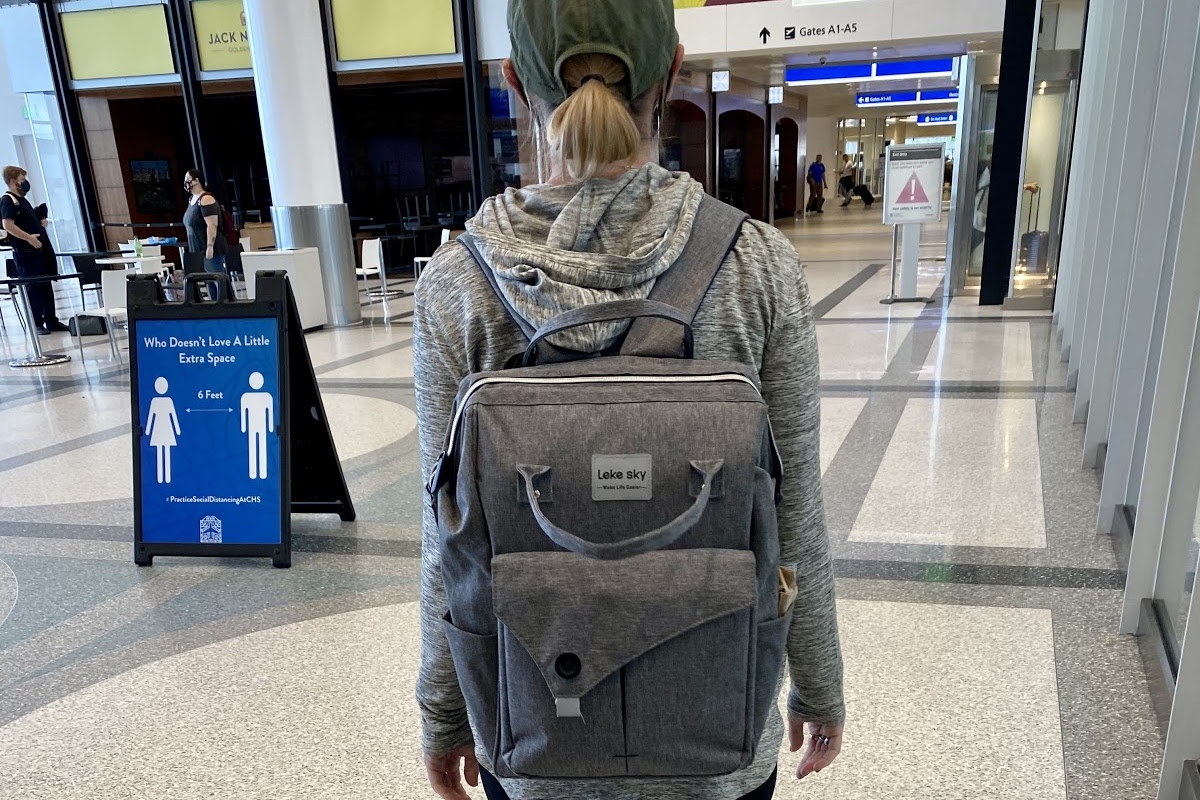 back of woman with backpack in airport on vacation on a budget