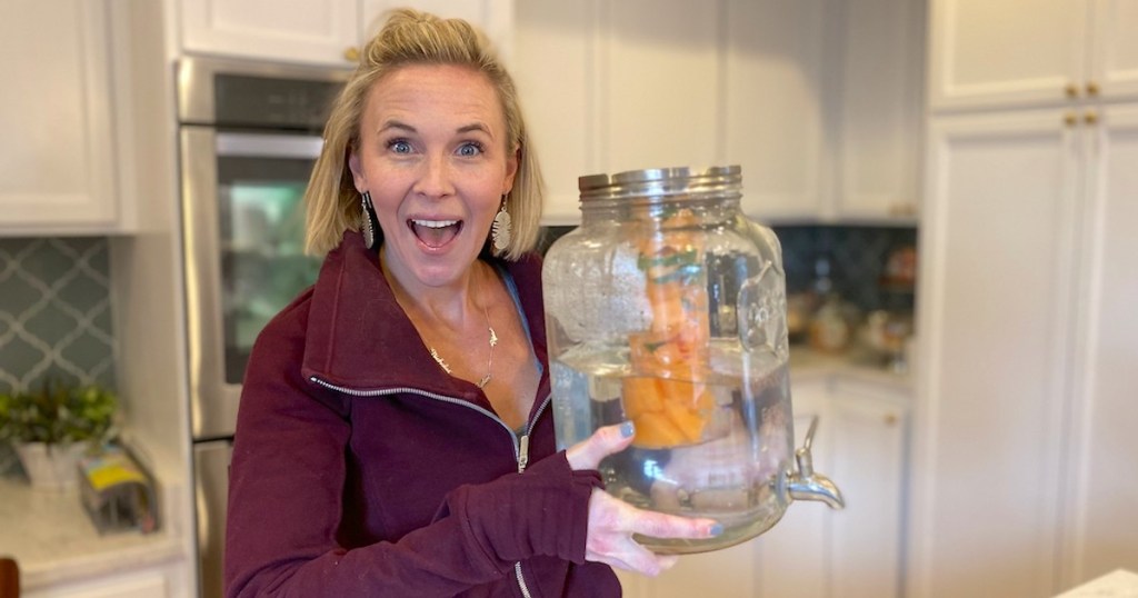 woman holding glass jug of fruit infused water
