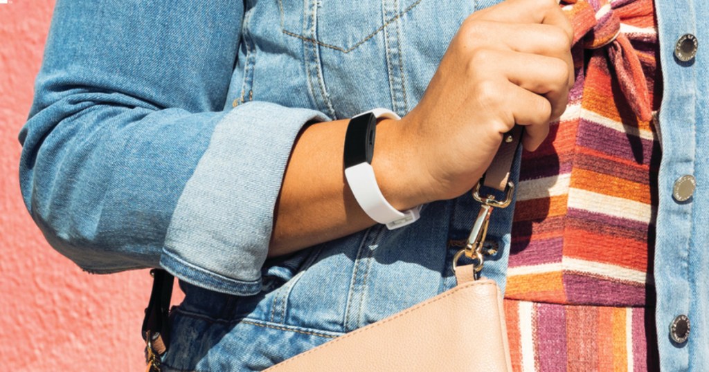 woman in jean jacket wearing white fitbit on arm