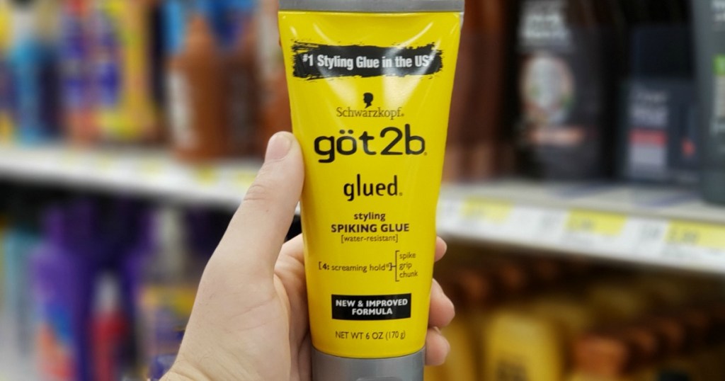 hand holding a bottle of got2b glued styling gel in front of haircare products at a store
