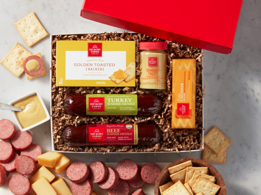 crackers, cheese, sausage and mustard in gift box with food on table