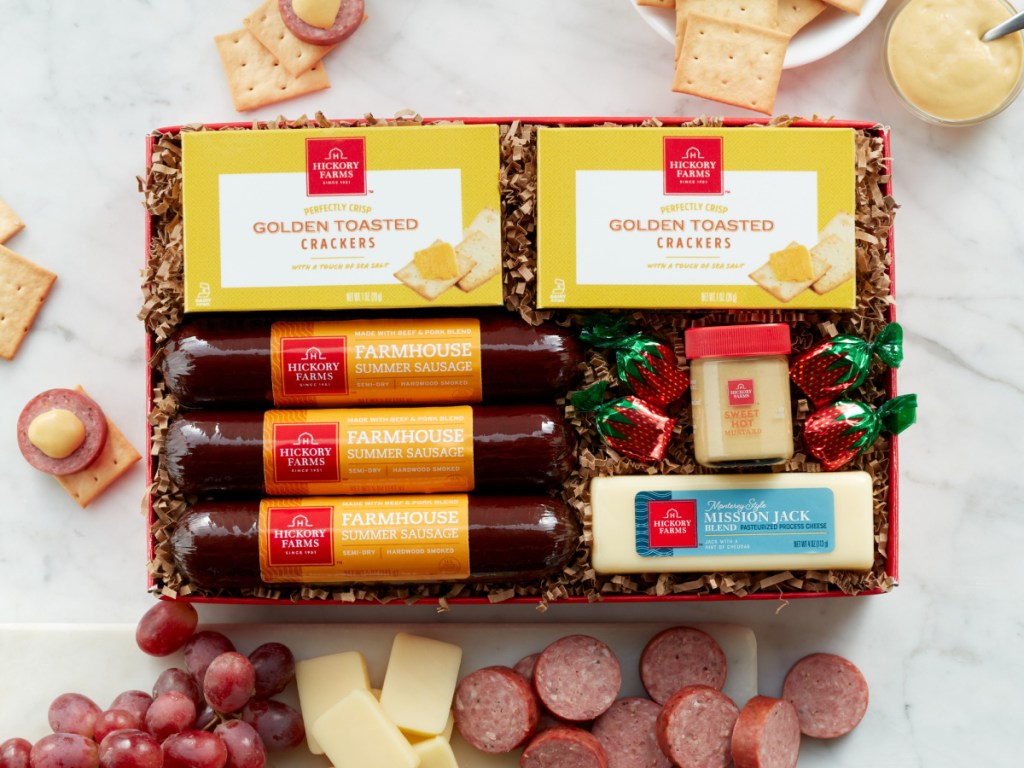 cheese, sausage and mustard gift box with cheese sausage grapes and crackers on table