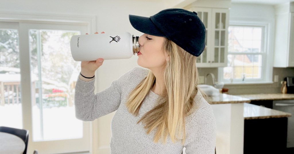 woman drinking out of white hydroflask water bottle