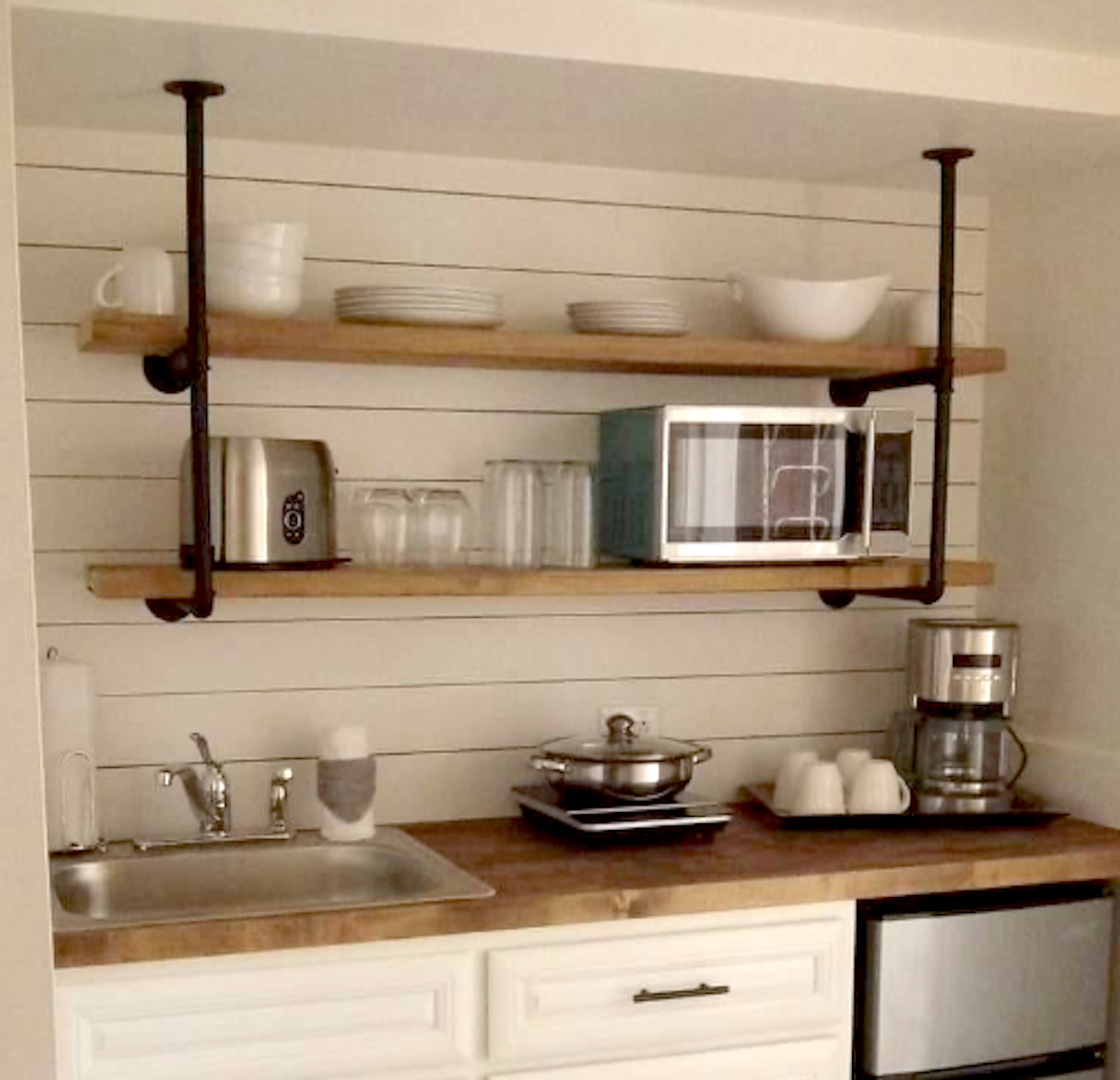 kitchen wall with shiplap and wood and iron pipe shelves with dishes on them