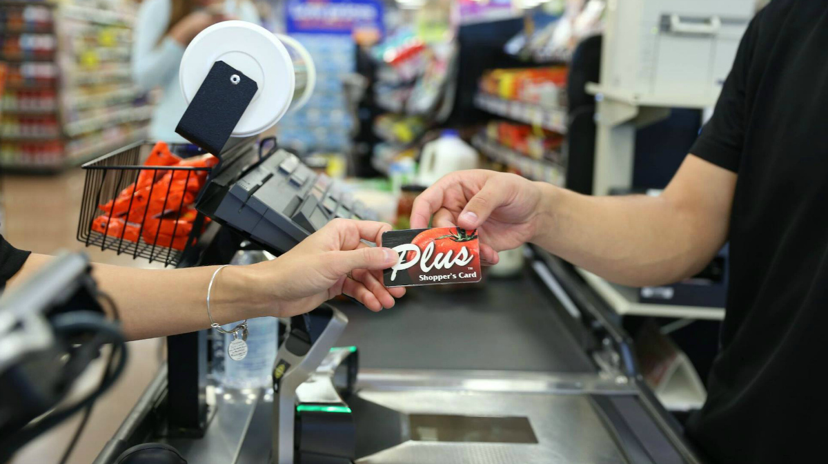 person handing over kroger shopping card in checkout line