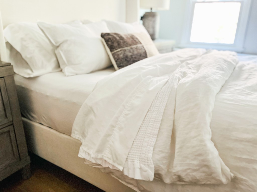 close up of side of master bed with white bedding and pillows