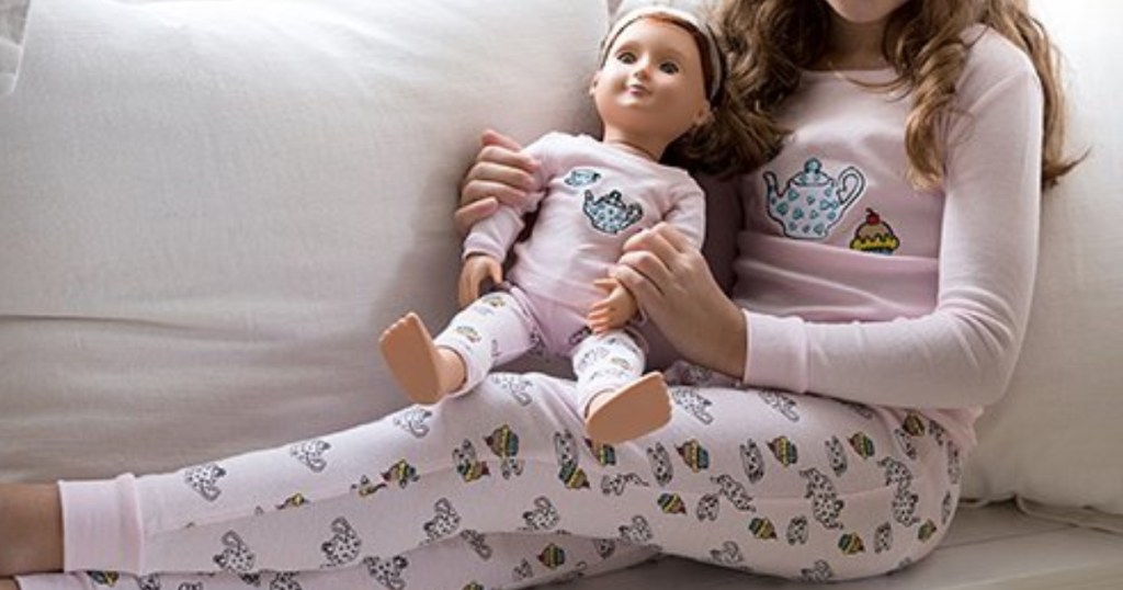 little girl holding doll both wearing the same pajamas