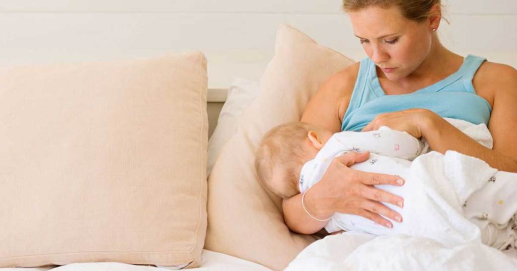 mom nursing baby discreetly on a bed