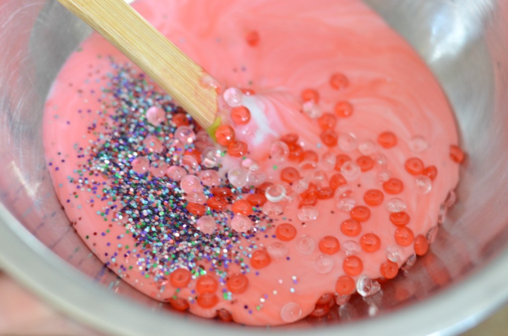 mixing up slime in a bowl with beads and glitter