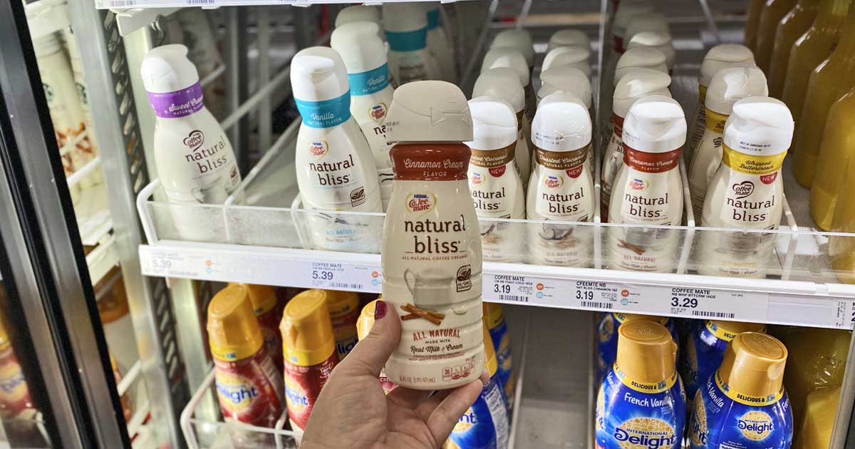 woman's hand holding a bottle of Coffee-Mate Natural Bliss Creamer in a store