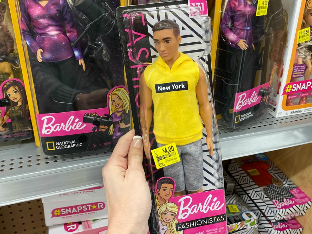 hand holding Ken doll in package in front of store display