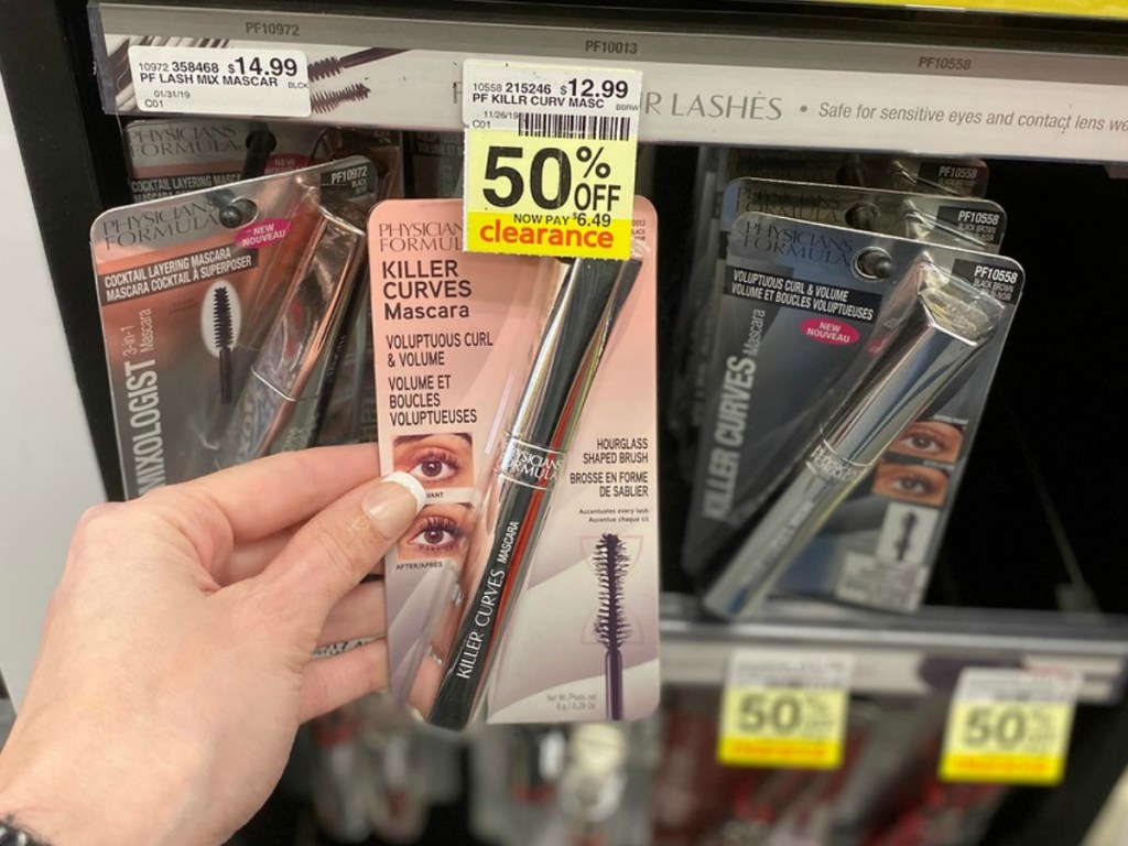 hand holding mascara in packaging in front of store shelf