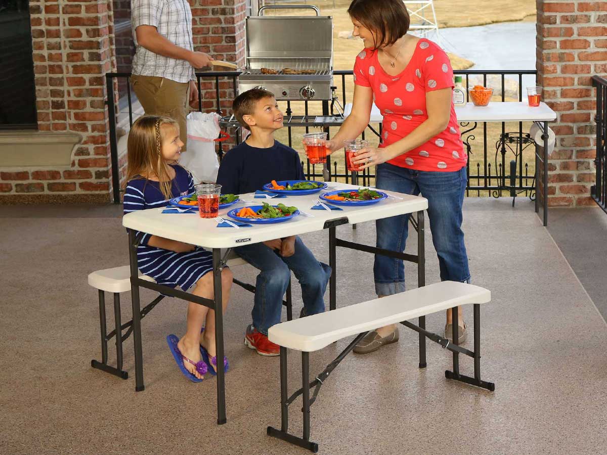 Family using a foldable picnic table and benches on a patio