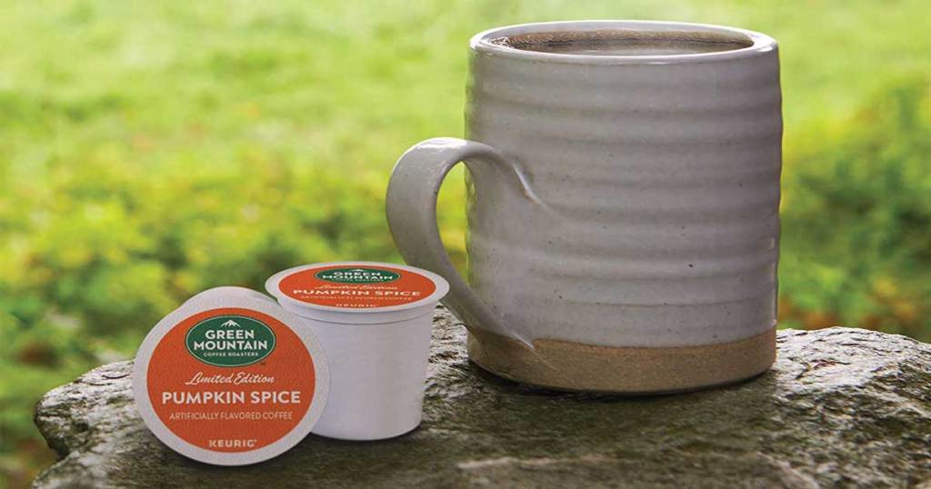 lifestyle picture of Green Mountain Roasters Pumpkin Spice K-Cups sitting next to a cup of coffee with grass in the background