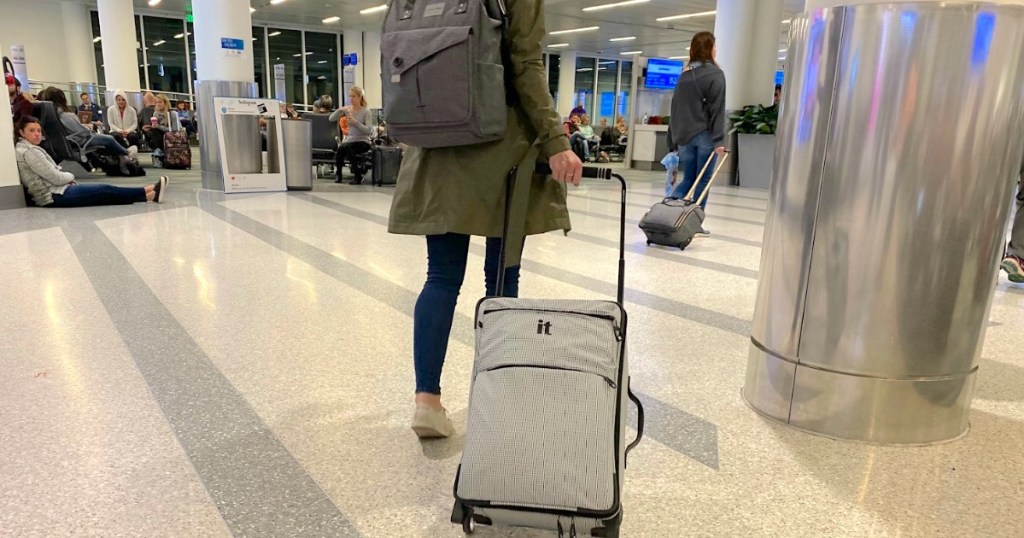 woman wearing backpack and pulling carryon luggage in airport