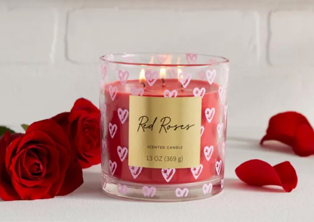 lit red roses candle on counter with red rose petals 