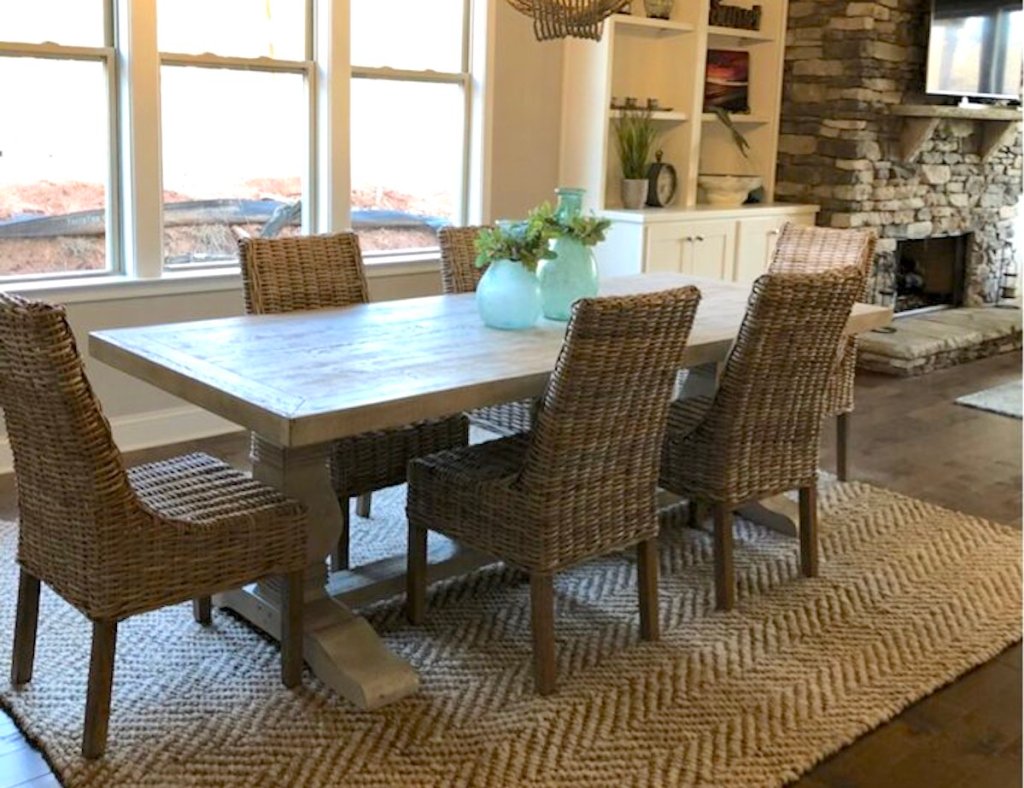 dining room table and chairs on rug in front of stone fireplace