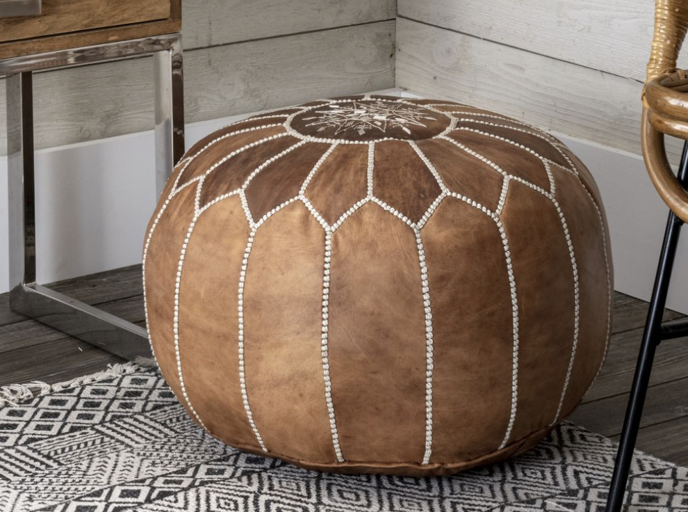 brown leather pouf sitting on rug in corner of room