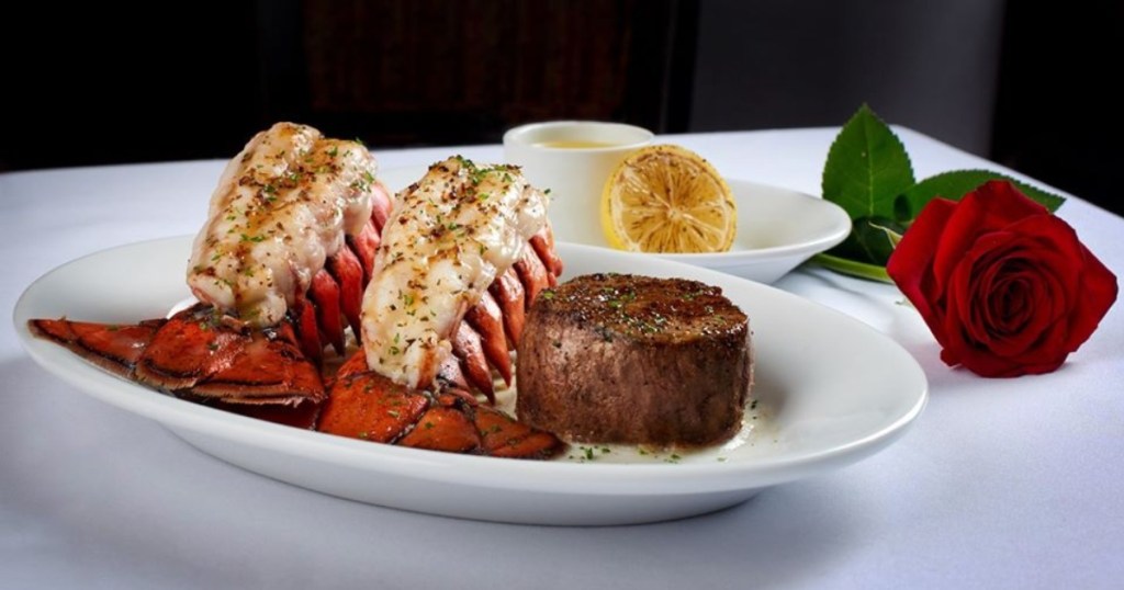 steak and lobster on a plate next to a rose
