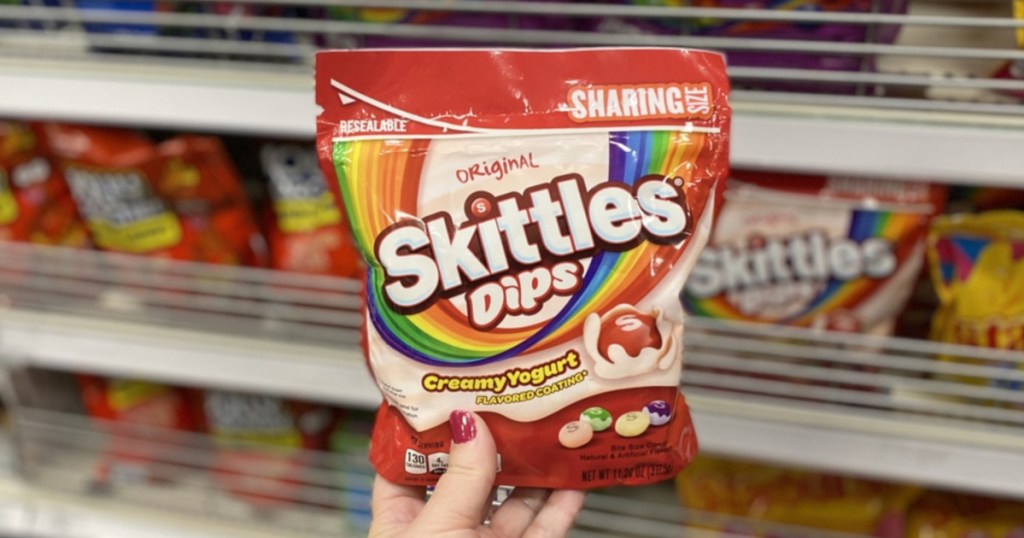 woman's hand holding skittles candies