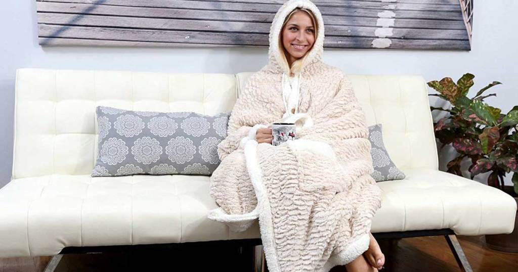 model sitting on a couch wearing Chic Home Design Hooded Snuggle Blanket