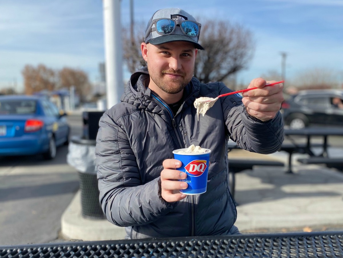 man holding a spoonful of DQ Blizzard and dish